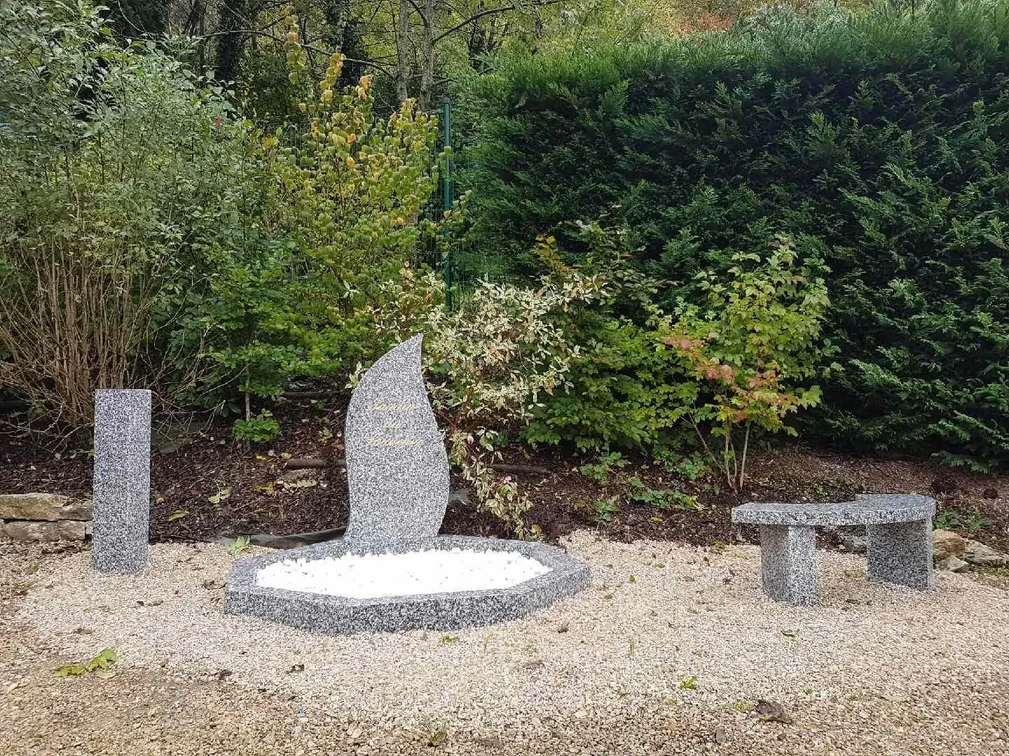 Monument cinéraire contemporain en granit avec banc assorti dans un cadre paysager.
