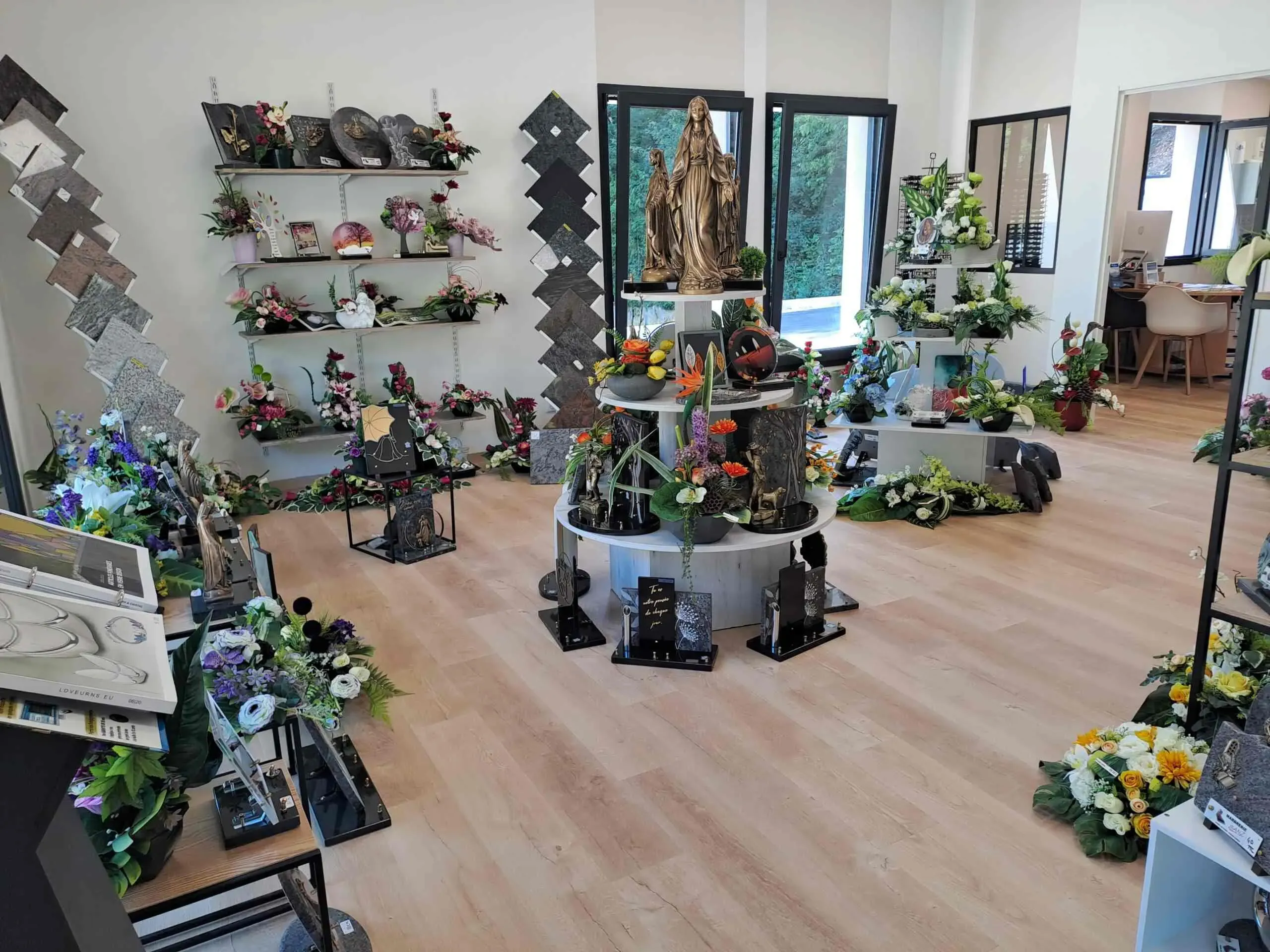 Intérieur lumineux d'un magasin présentant des compositions florales et plaques.